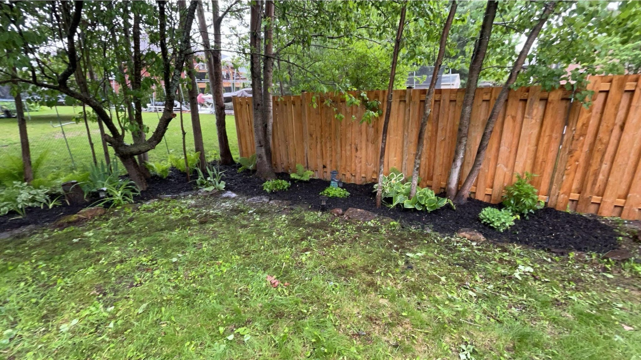 Garden bed landscaping with fresh mulch along a wooden fence